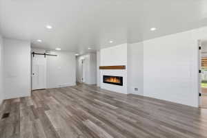 Spacious room featuring vinyl flooring, recessed lighting, and an electric fireplace with a wood mantle