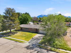 Brick-clad rambler home featuring a large front lawn and an attached garage