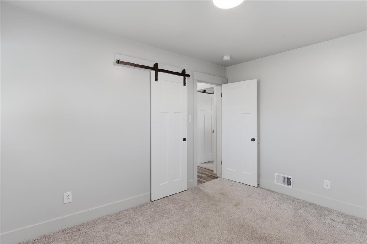 Bedroom featuring light gray walls, plush gray carpeting, and white trim
