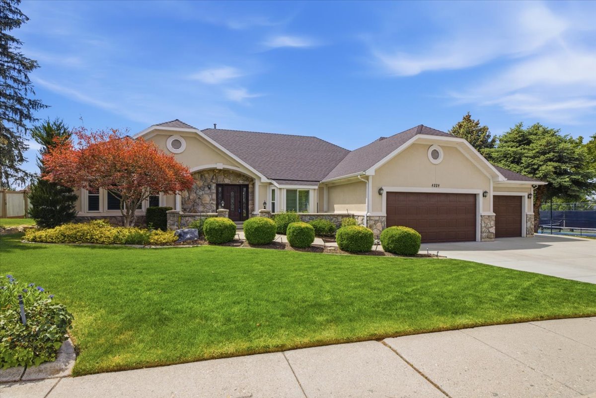 Stucco and stone exterior featuring a dark asphalt shingle roof