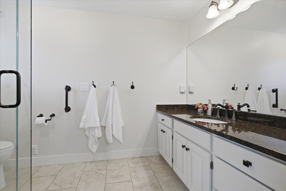 Bathroom featuring a white vanity with dark countertop, large wall-mounted mirror, and glass-enclosed shower