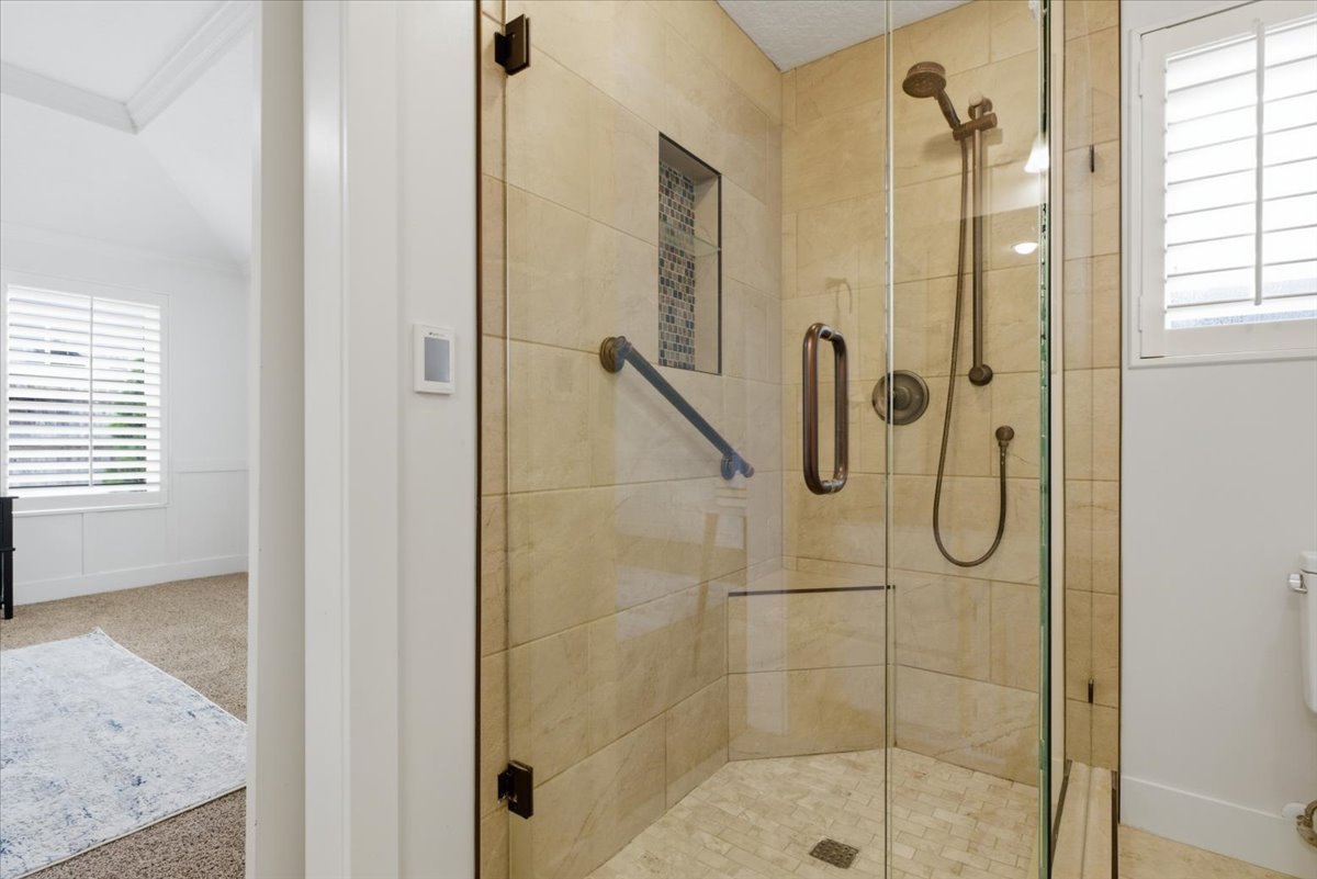 Glass-enclosed shower featuring large format tile walls, a mosaic tile niche, and bronze fixtures