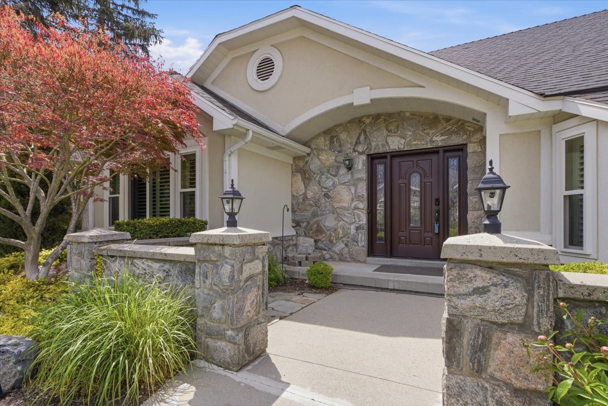 Stone veneer facade with an arched portico entry and a dark wood-finish double door