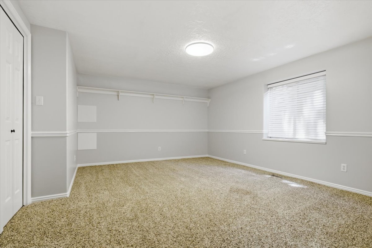 Spacious room featuring neutral carpet flooring and light gray walls with chair rail molding