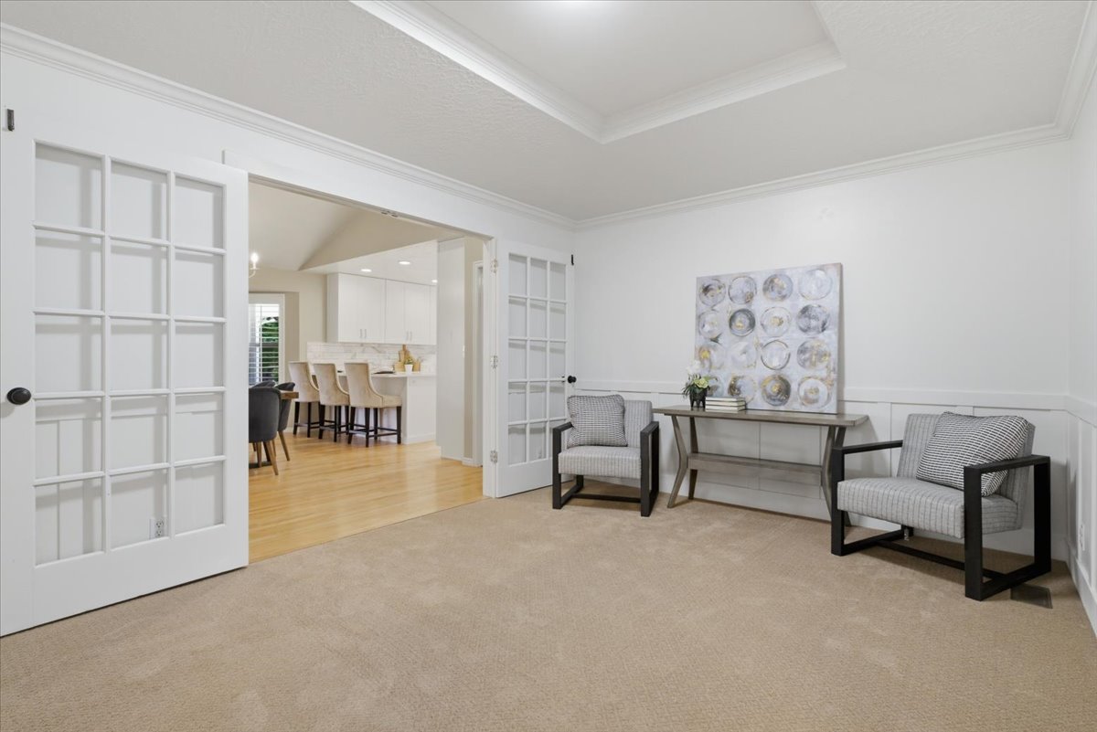 Carpeted room with white paneling and crown molding