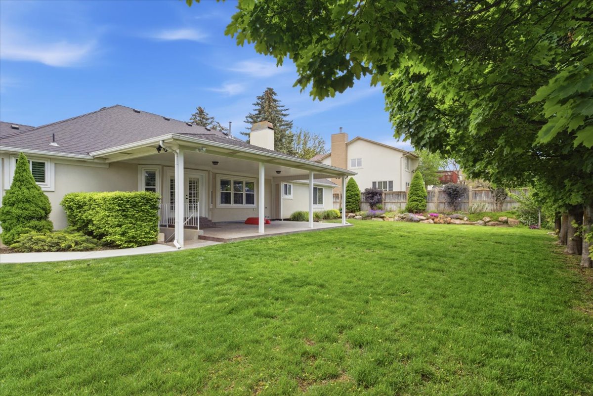 Expansive green lawn with mature trees and a covered patio