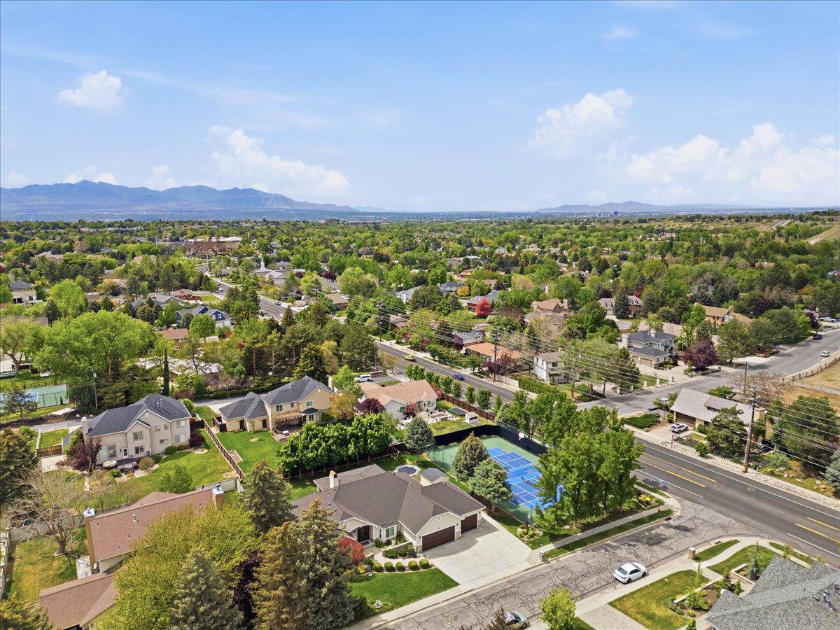 Expansive residential area featuring numerous single-family homes with diverse architectural styles, mature landscaping, and a mountainous backdrop