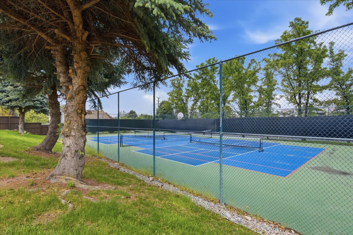 Regulation-sized tennis court with a blue playing surface and green surrounding area