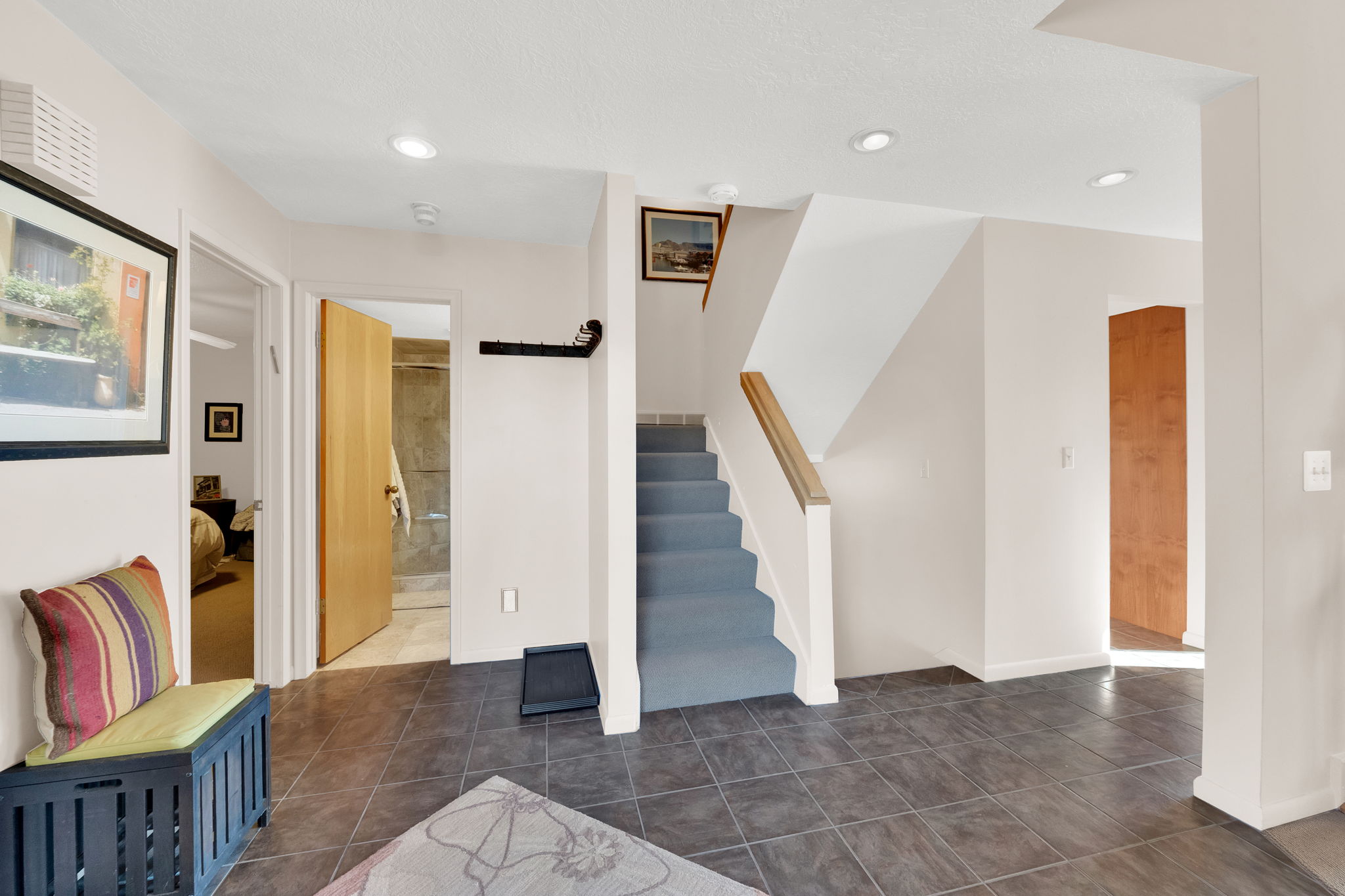 Entryway featuring dark tile flooring, a carpeted staircase with a wood handrail, and recessed lighting