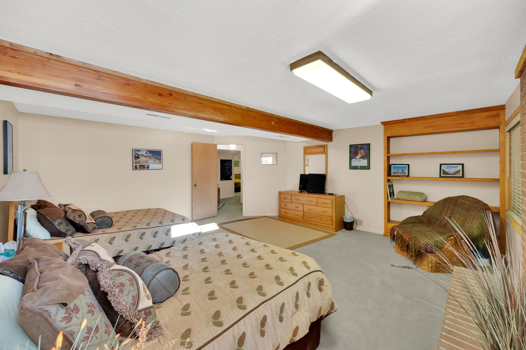 Carpeted room featuring exposed wood beams and a built-in wooden bookshelf