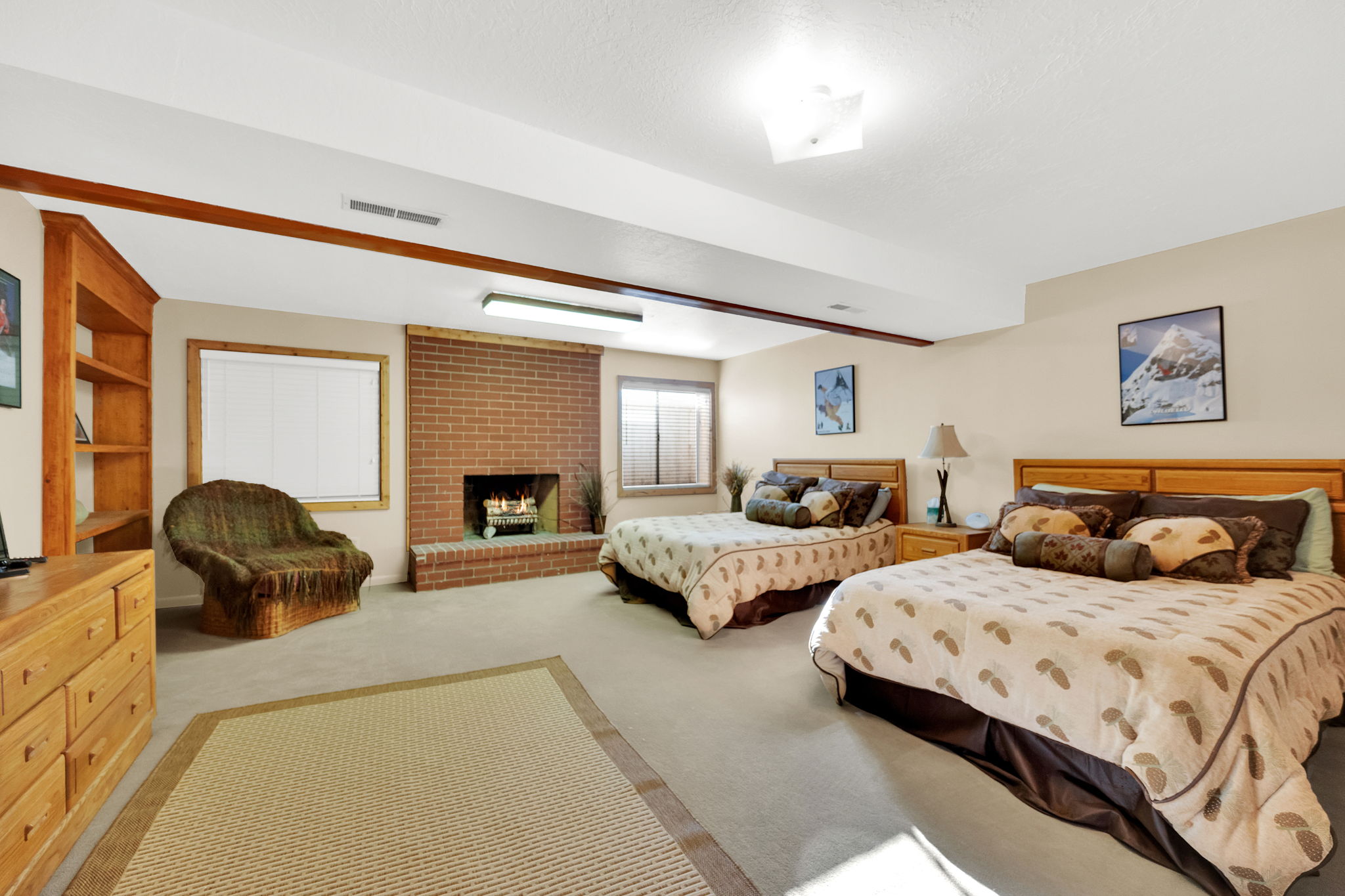 Spacious room featuring a brick fireplace, built-in wooden shelving, neutral-toned walls, recessed lighting, and carpet flooring