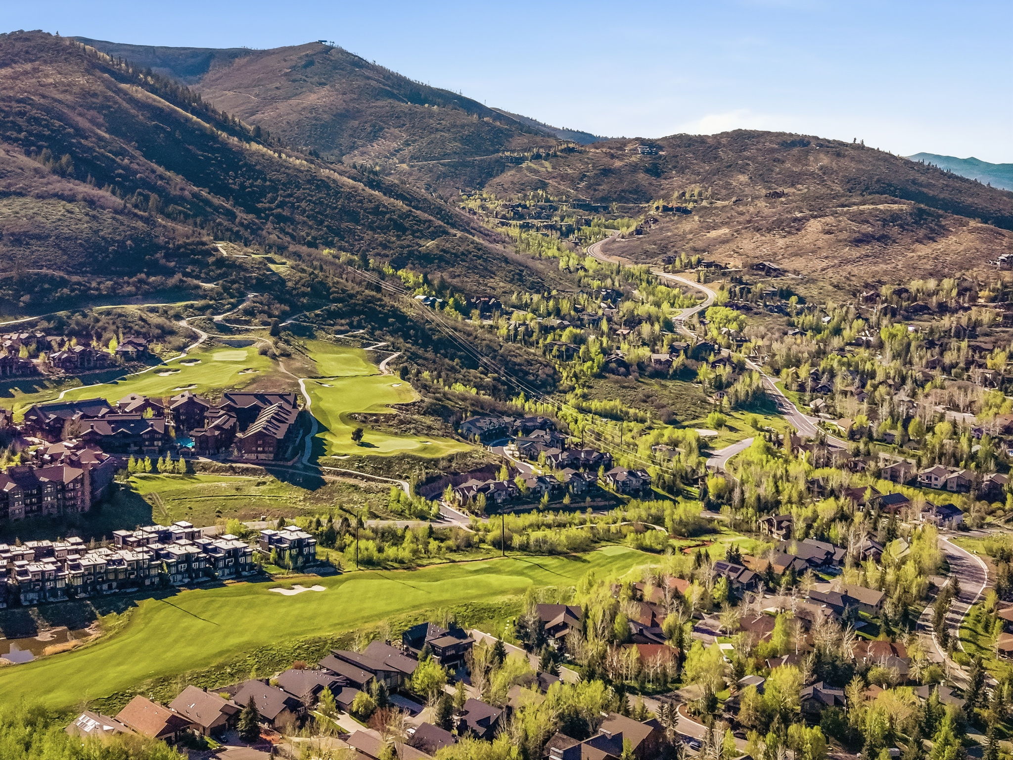 Expansive golf course community with mountain terrain, mature deciduous trees, and residential properties