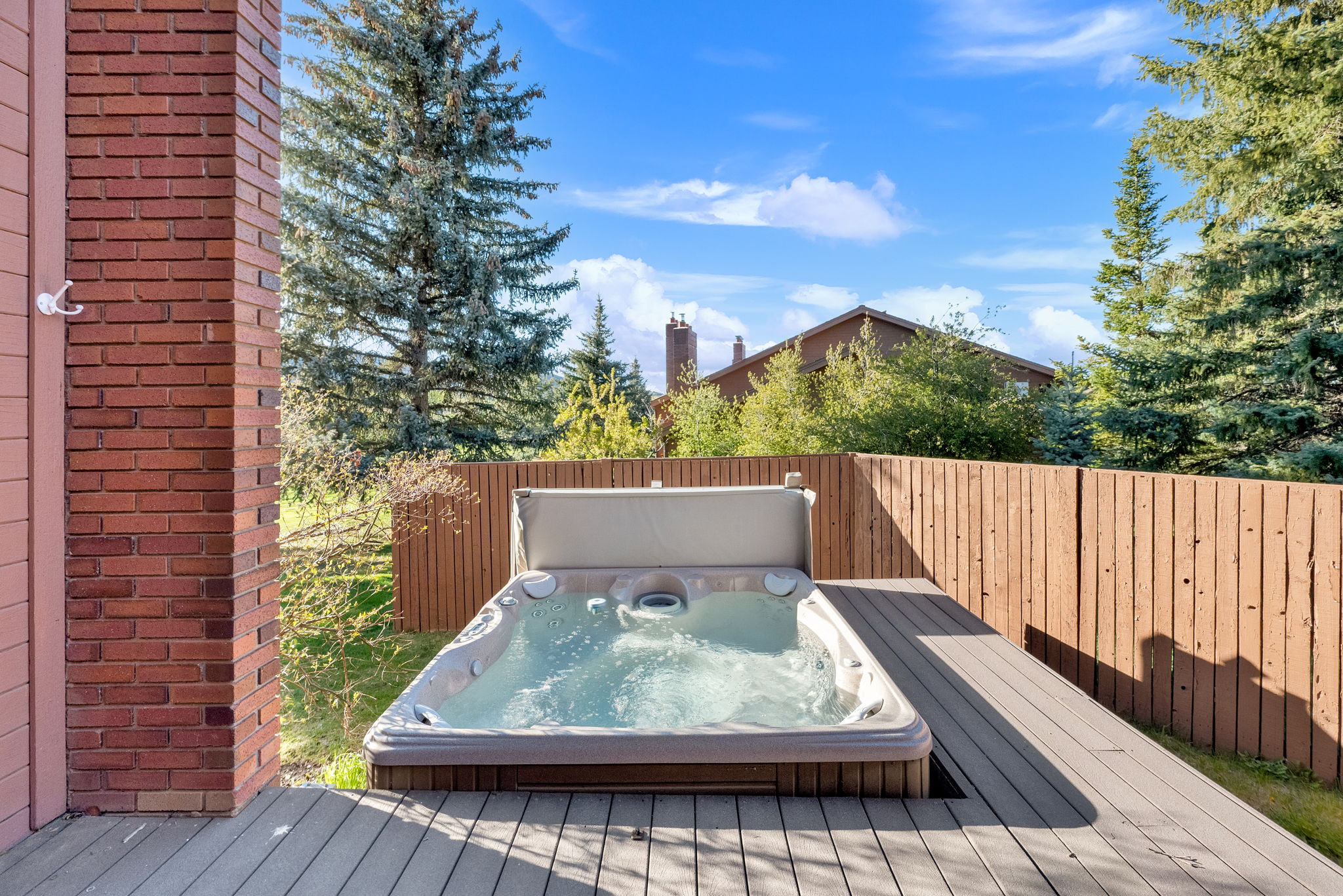 Outdoor hot tub on a composite deck, bordered by a wood privacy fence