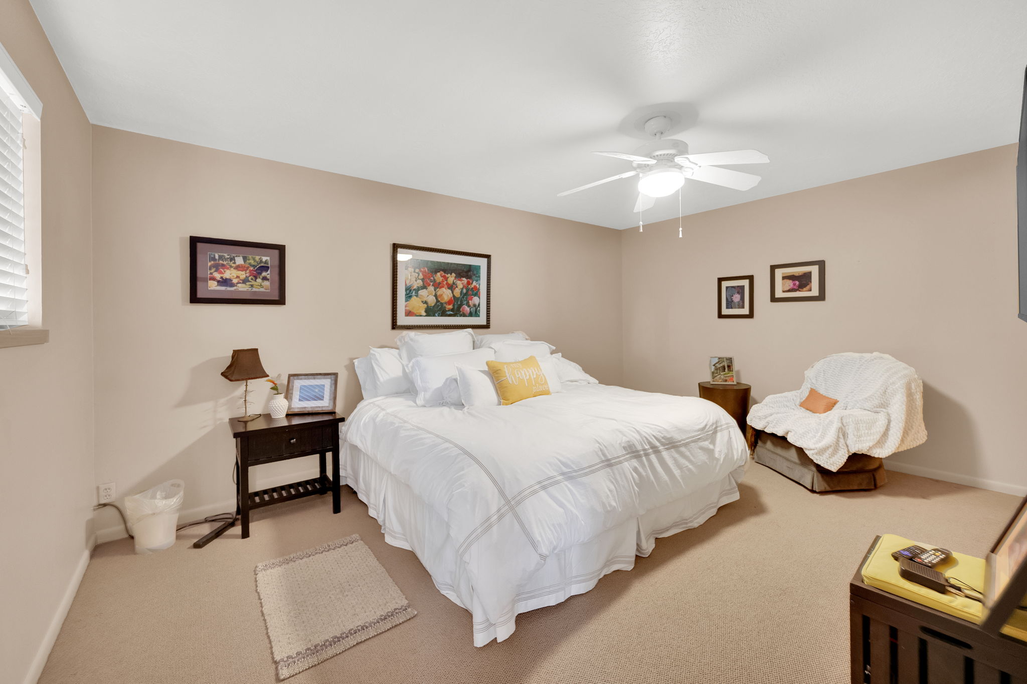 Plush carpet flooring, a ceiling fan with integrated lighting, and neutral wall tones define this inviting room