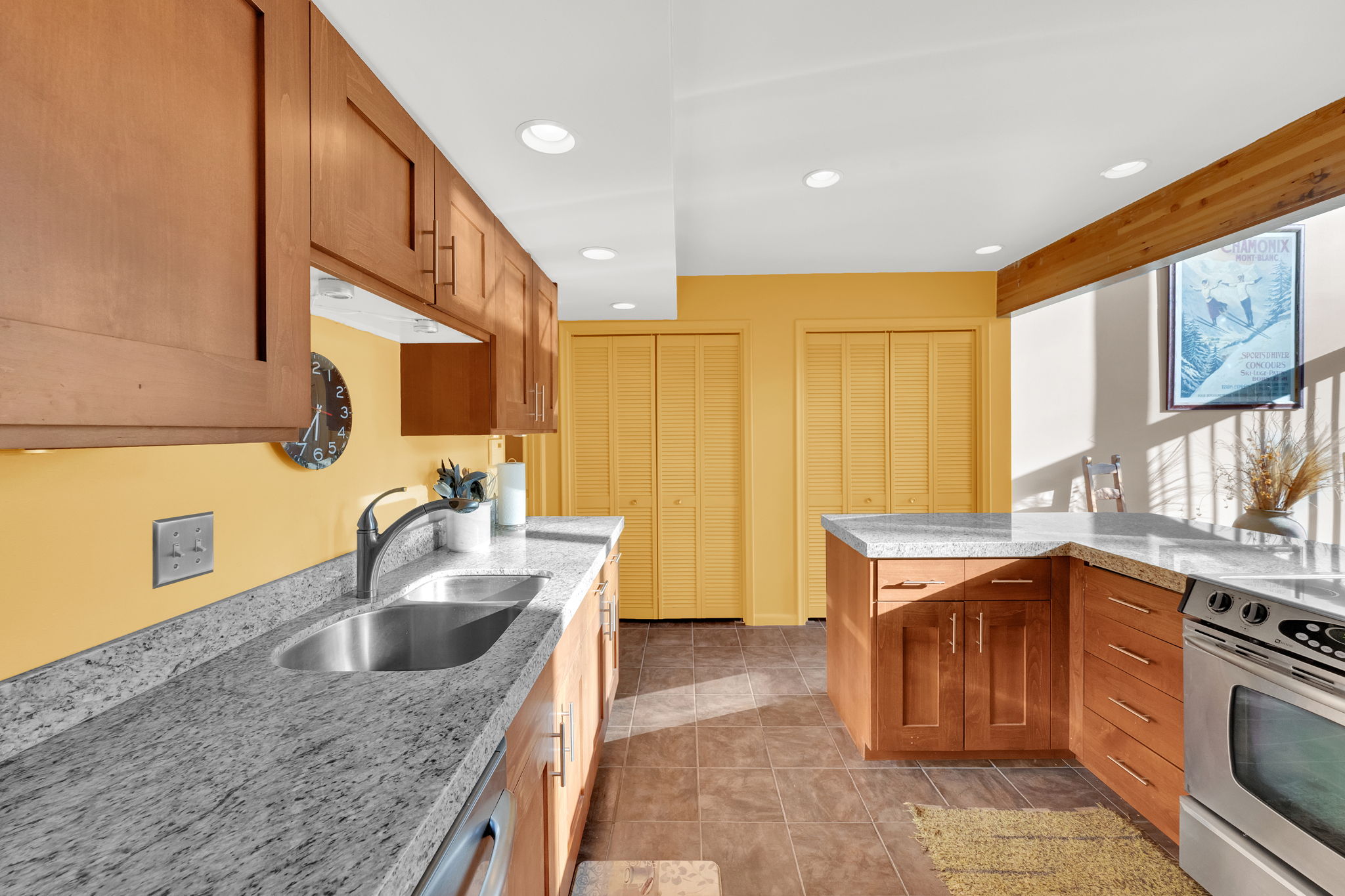Kitchen featuring wood cabinetry with contemporary hardware, light-toned countertops, and a stainless steel sink with a gooseneck faucet