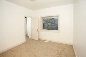 Neutral-toned room featuring light beige carpeting and white painted walls