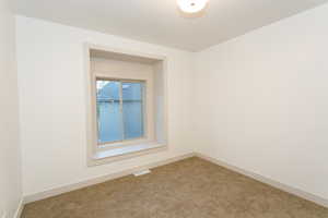 Recessed window with a deep sill, neutral wall paint, ceiling-mounted light fixture, and carpet flooring
