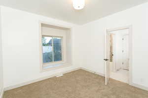 Neutral wall tones featuring a recessed window with a sill, carpet flooring, and a ceiling-mounted light fixture
