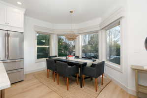 Dining area featuring a bay window, wood-finish flooring, and a contemporary chandelier