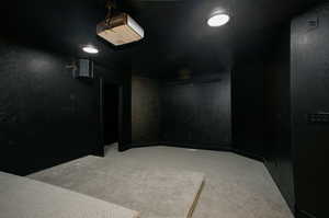 Dedicated entertainment space featuring a ceiling-mounted projector, recessed lighting, and wall-mounted speakers