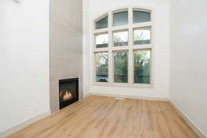 Floor-to-ceiling arched window with multiple panes, wood-finish flooring, and a tiled fireplace surround