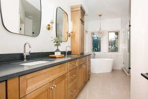 Double vanity with wood cabinetry, integrated sinks, and dark countertops