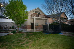 Rear exterior featuring a brick foundation, stucco siding, and a second-story balcony with wood railing