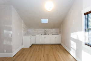 Compact kitchen area featuring white cabinetry, a stainless steel sink, and an integrated cooktop