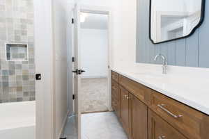 Bathroom featuring a wood-finish vanity with an integrated sink, white countertop, and chrome faucet