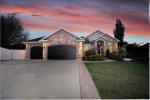 Stone and brick facade residence featuring a multi-car garage with arched entrances, a concrete driveway, and a manicured lawn