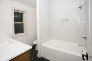 Bathroom featuring a white subway tile shower surround with an inset niche, a white bathtub, and chrome fixtures