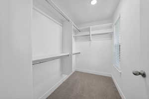2nd Floor Primary Suite Walk-in closet featuring white built-in shelving,