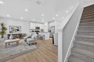 Open-concept living space with recessed lighting and light wood LVP flooring