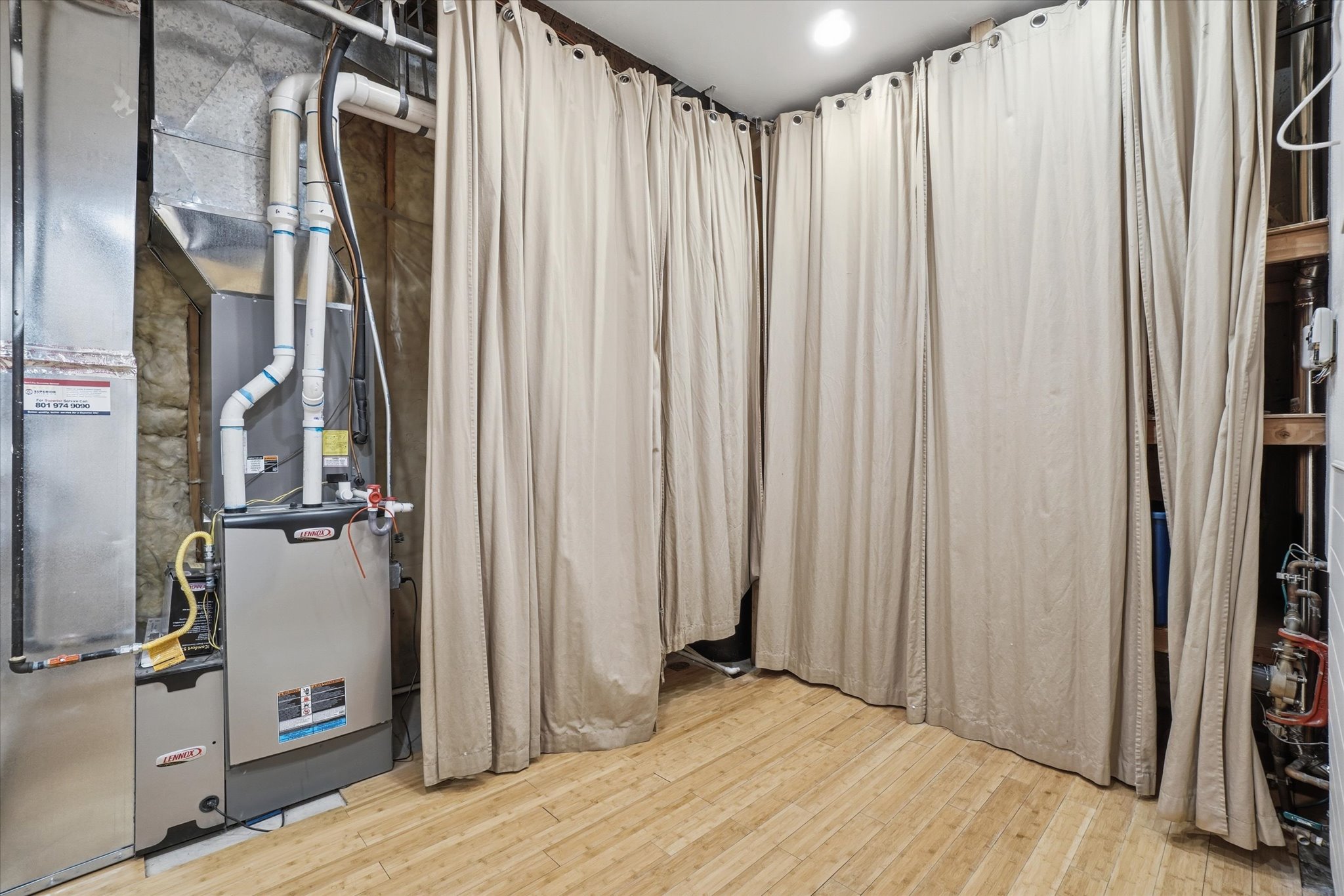 Dedicated utility area featuring a furnace system, exposed ductwork, and light wood-finish flooring