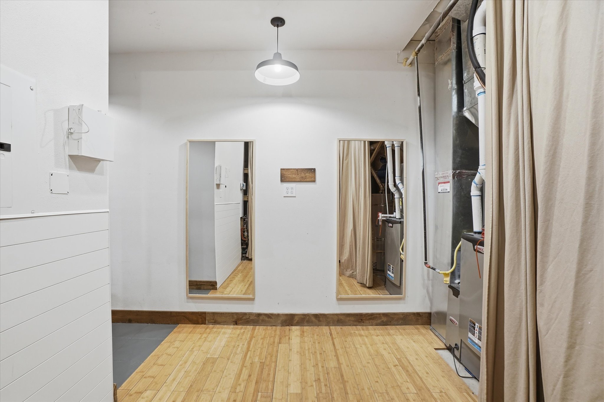 Utility room featuring light wood-finish flooring, white shiplap paneling, and a modern pendant light fixture