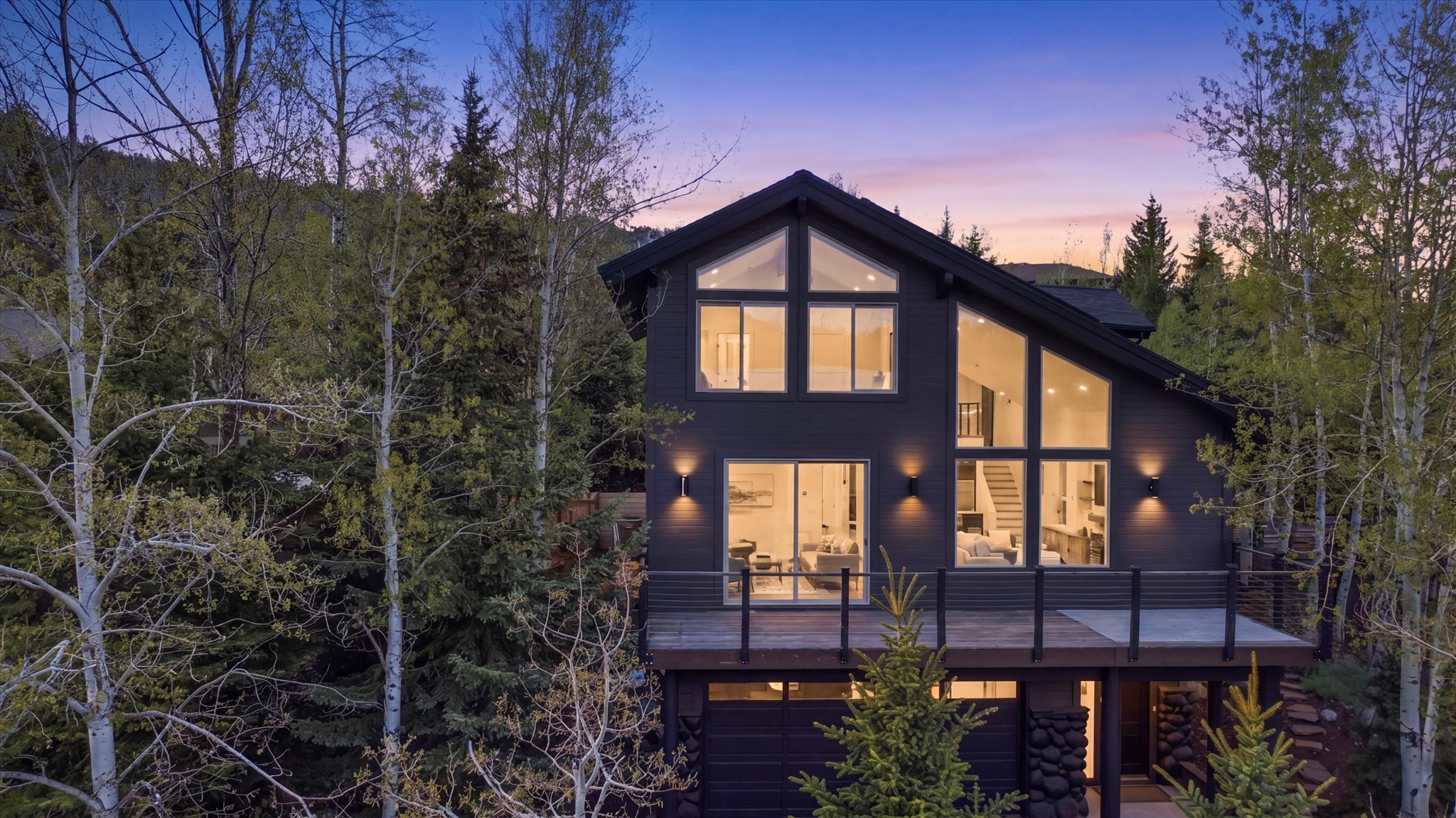 Contemporary multi-level residence featuring dark siding, a gable roof, and extensive floor-to-ceiling windows
