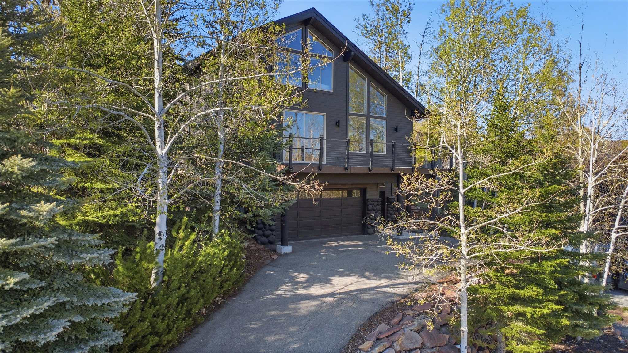 Contemporary multi-level residence featuring dark siding, a gable roof, and extensive floor-to-ceiling windows