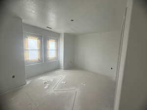 Unfinished interior room with two windows, white walls, and baseboard trim