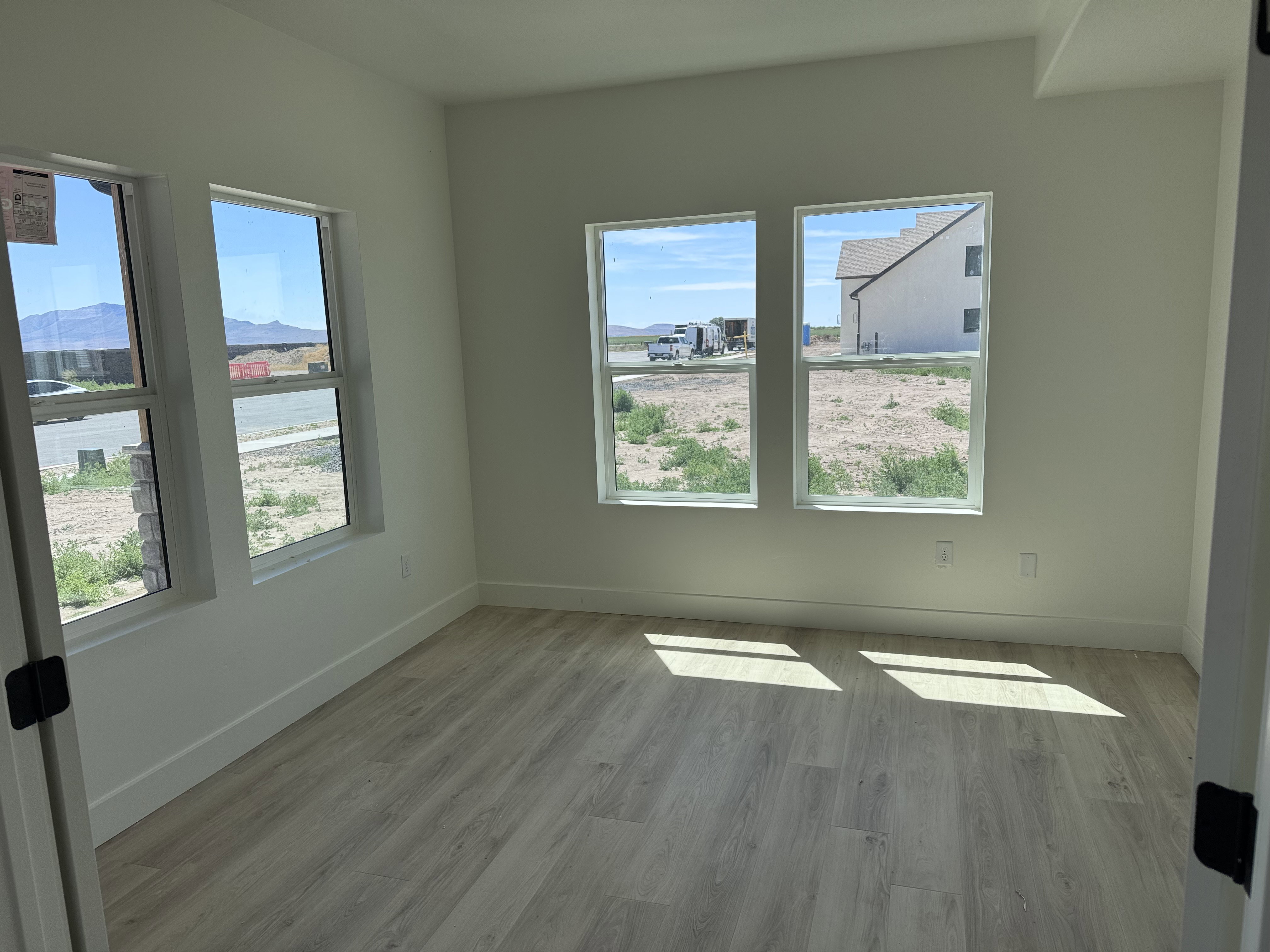 Room featuring light wood-finish flooring, white walls, and multiple windows