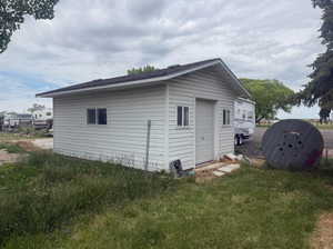 White vinyl-sided outbuilding with an attached garage door and multiple windows