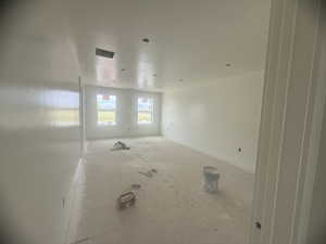 Spacious room with uninstalled flooring, recessed lighting, and dual windows