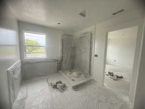 Light-filled interior space featuring a large window, recessed lighting, and a walk-in shower enclosure
