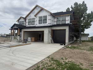 New construction residence featuring a two-story design with a covered entryway, a prominent two-car garage, and a newly poured concrete driveway