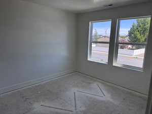 Bright interior space featuring two large windows, white walls, and a subfloor ready for finish