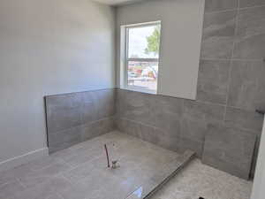 Shower area featuring large format gray tile on walls and floor, a linear drain, and a window with trim