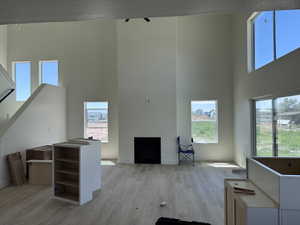 Two-story open-concept living space with high ceilings, light wood-finish flooring, and a contemporary fireplace