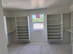 Spacious room featuring multiple built-in shelving units, a recessed ceiling light, a window providing natural light, and a vent