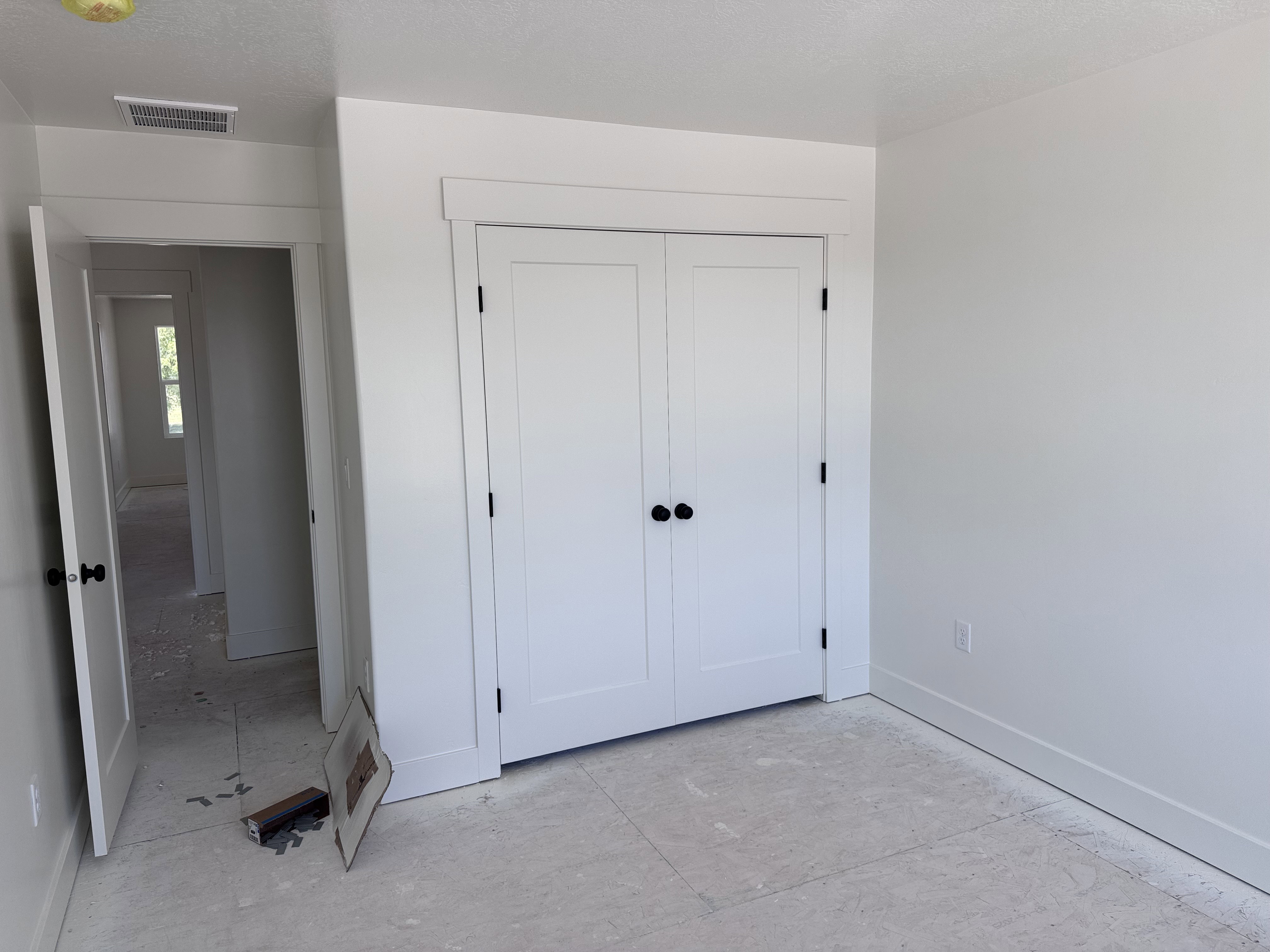 White bi-fold closet doors with matte black hardware, white baseboards, white door casings, and a white interior wall finish
