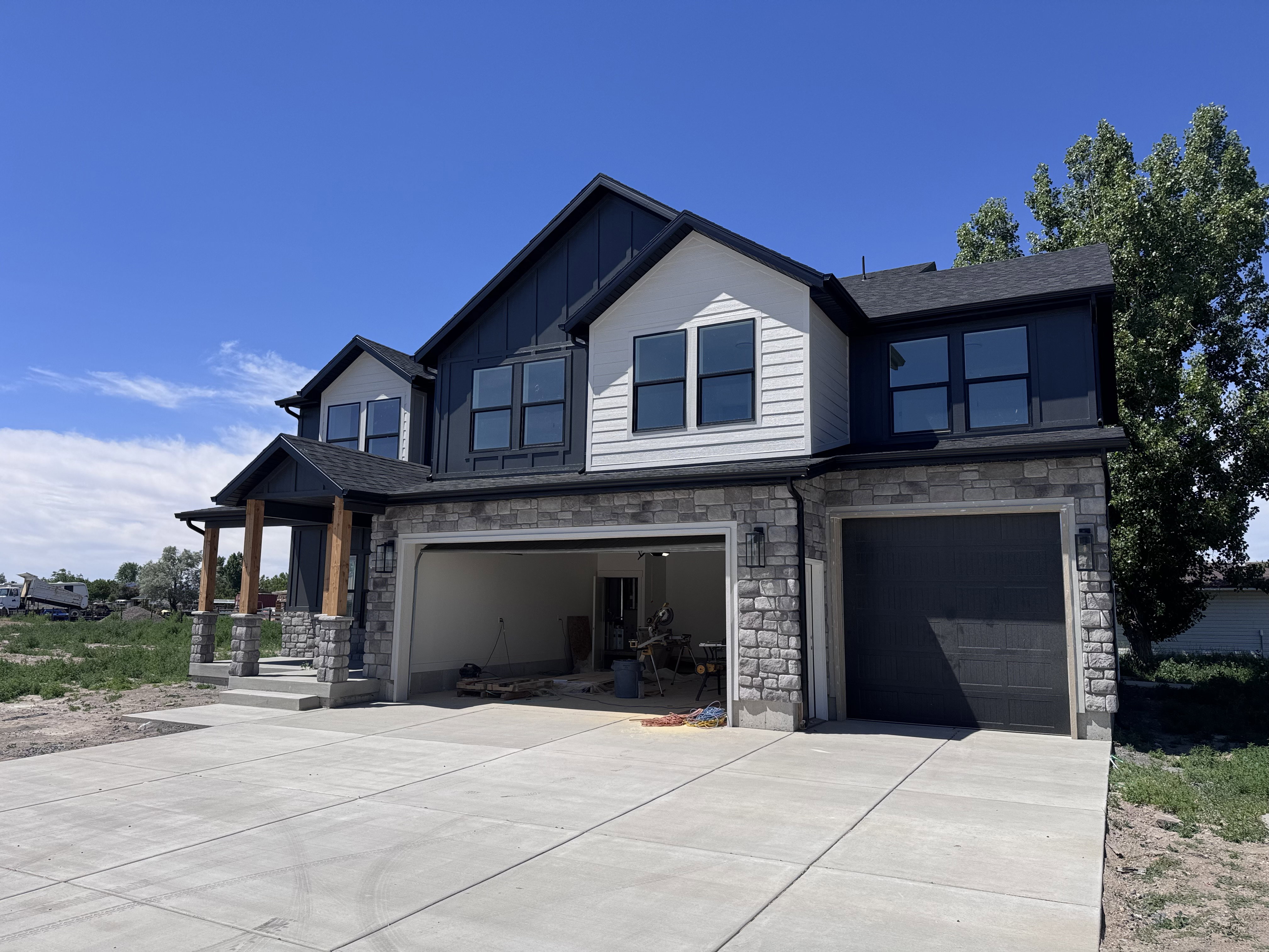 Contemporary exterior featuring stone veneer, dark siding, and white paneling accents