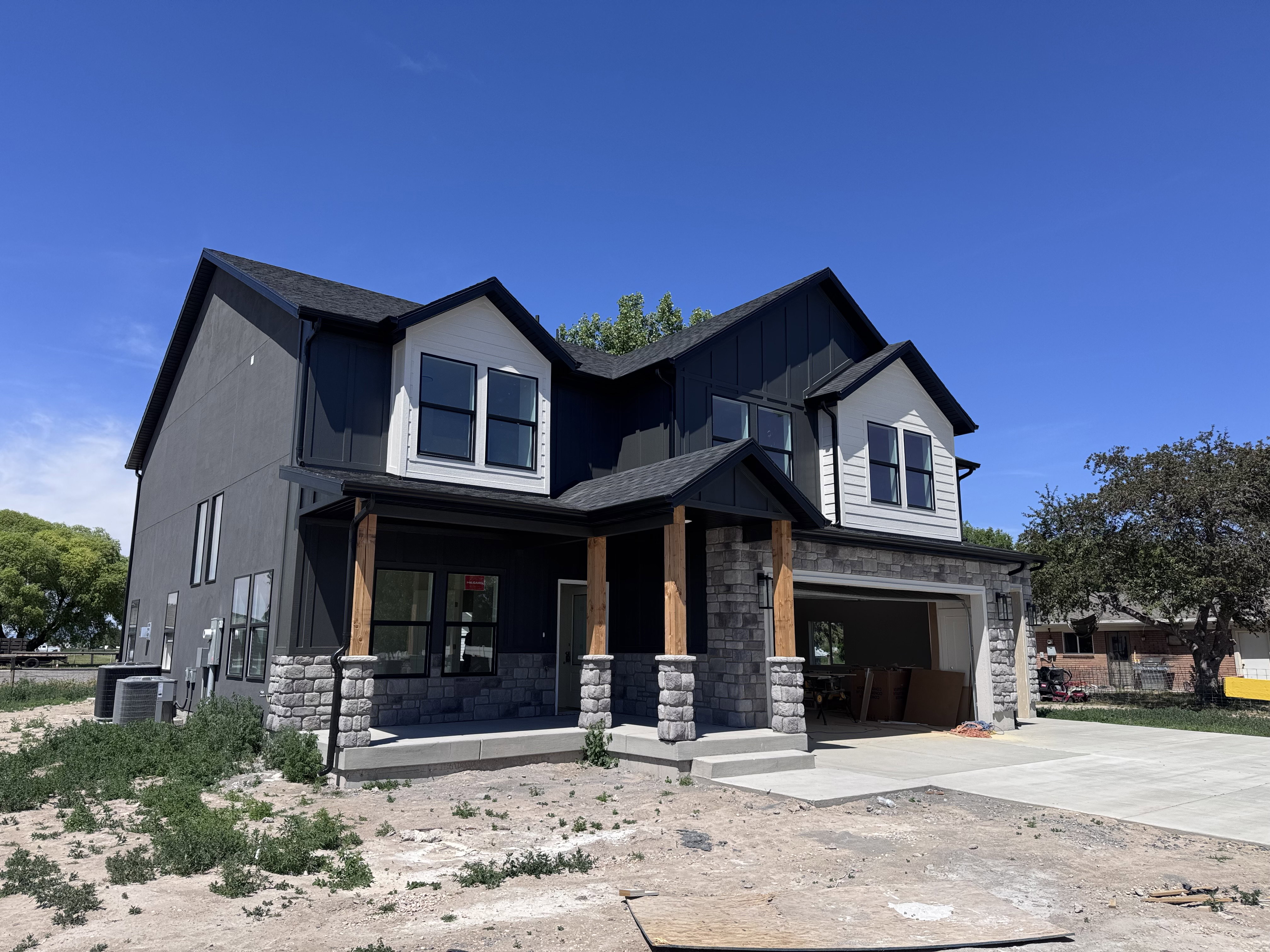 Contemporary two-story residence with a dark facade, white gables, and black-framed windows